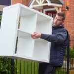 Furniture removal, a man taking a heavy shelving unit out of a home
