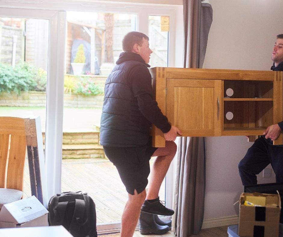 Furniture removal- 2 men removing a TV stand.