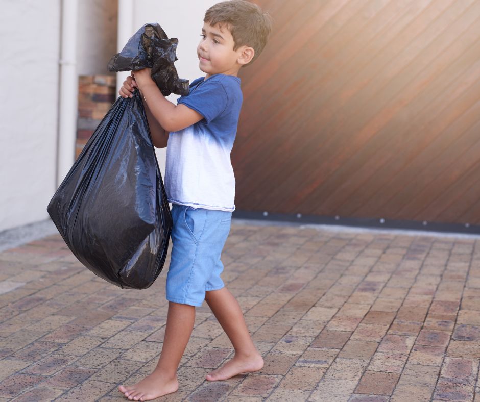 A young boy taking out the trash